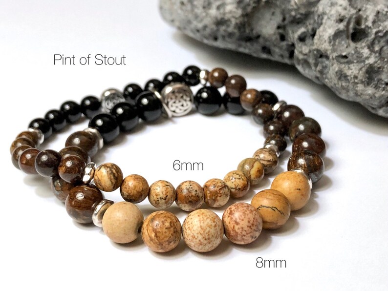 May include: Two bracelets with brown and black beads. The smaller bracelet has 6mm beads and the larger bracelet has 8mm beads. The larger bracelet has a silver charm with a Celtic knot design. The text "Pint of Stout" is visible in the image.