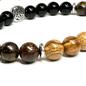 May include: A beaded bracelet with black and brown beads, a silver Celtic knot charm, and a silver spacer bead.
