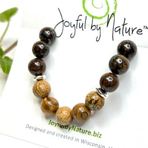 May include: A brown and tan gemstone bracelet with silver spacer beads. The bracelet is on a white card with the text "Joyful by Nature" and "JoyfulbyNature.biz".