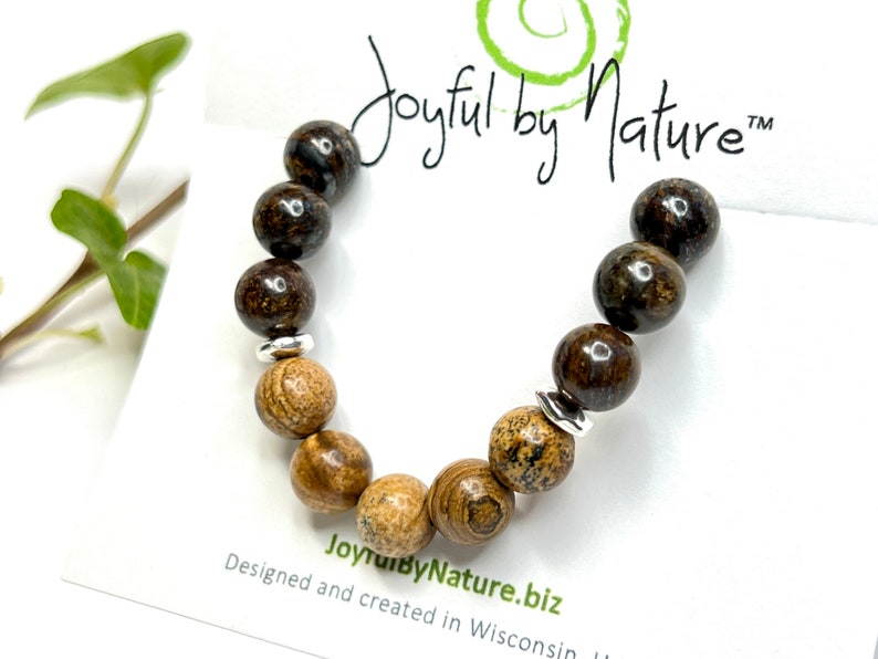 May include: A brown and tan gemstone bracelet with silver spacer beads. The bracelet is on a white card with the text "Joyful by Nature" and "JoyfulbyNature.biz".