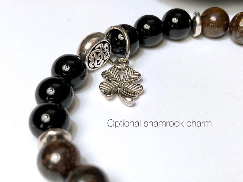 May include: Black and brown beaded bracelet with a silver shamrock charm. The bracelet has a silver bead with a Celtic knot design.