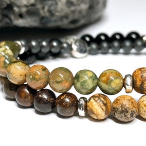 May include: A multi-strand bracelet with brown, green, and black beads. The bracelet has silver metal spacers between the beads.