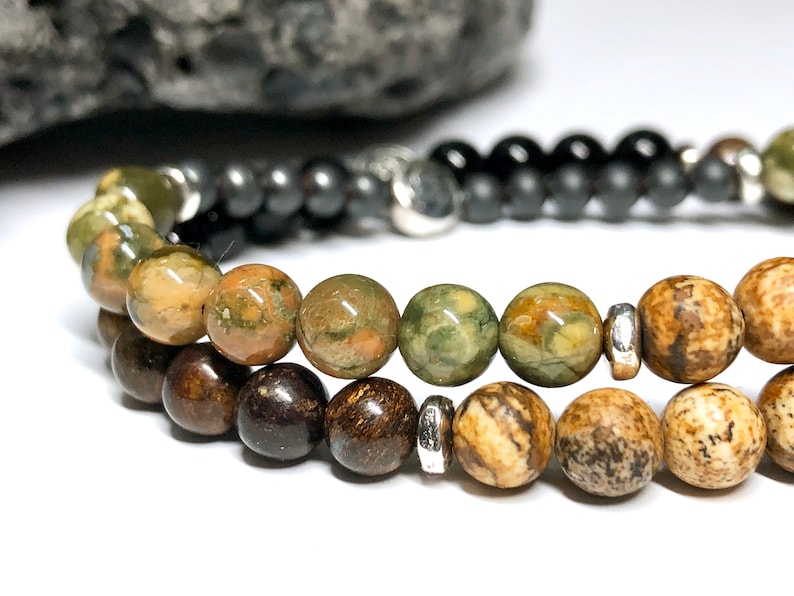 May include: A multi-strand bracelet with brown, green, and black beads. The bracelet has silver metal spacers between the beads.