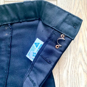May include: Black pants with a waistband and a label that says "Made in" and "Size 25" with a triangle symbol.