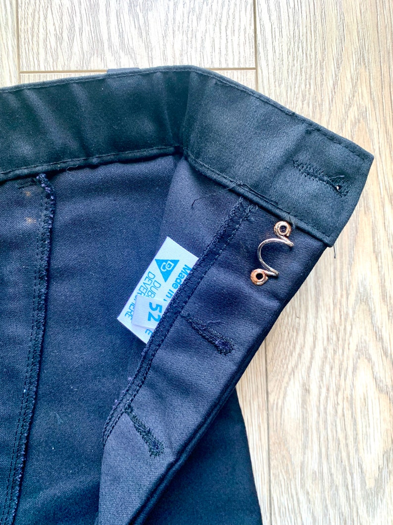 May include: Black pants with a waistband and a label that says "Made in" and "Size 25" with a triangle symbol.