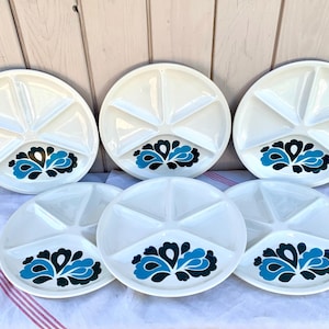 Op de afbeelding: Set van zes witte, gedeeld serveerschotels van keramiek met blauwe en zwarte bloemenmotieven. Elk bord heeft vijf secties.