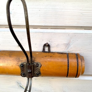 May include: A wooden coat rack with a metal hook. The rack is brown and has a natural wood finish. The hook is silver and has a simple design.