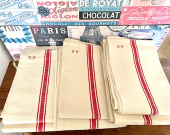 May include: A stack of four white linen tea towels with red stripes and the initials "GV" embroidered in red on each towel.