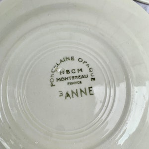 May include: White ceramic plate with a green inscription that reads "Porcelaine Opaque HBCM Montereau France E. Anne".