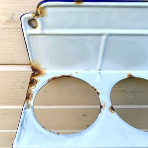 May include: White enamel shelf with three round holes and a blue rim. The shelf has some rust spots.