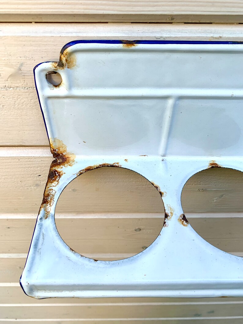May include: White enamel shelf with three round holes and a blue rim. The shelf has some rust spots.