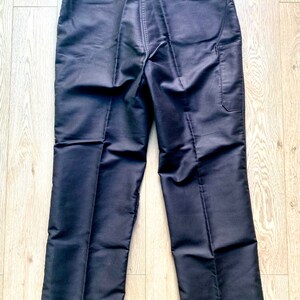 May include: A pair of black pants with a single back pocket and a small tag on the back waistband that reads "DUTCH & OVERSEAS".