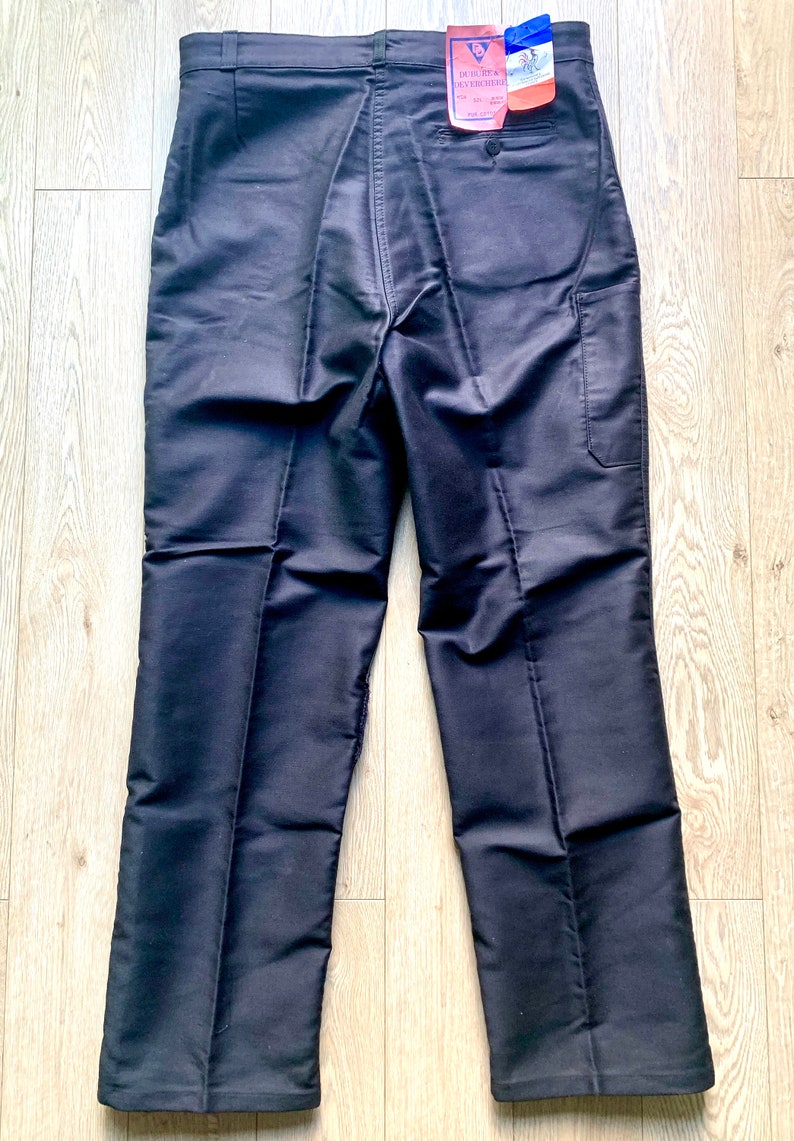 May include: A pair of black pants with a single back pocket and a small tag on the back waistband that reads "DUTCH & OVERSEAS".