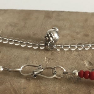 May include: Two necklaces with silver clasps. One necklace is made of clear beads and the other is made of red beads.