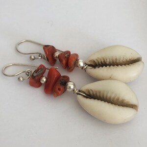 May include: A pair of silver earrings with red coral beads and white cowrie shells.