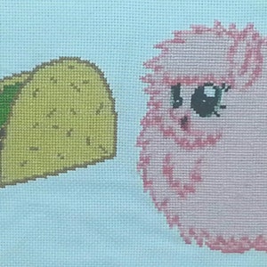 May include: Cross-stitch embroidery of the phrase "I love" with a yellow taco and a pink fluffy alpaca.