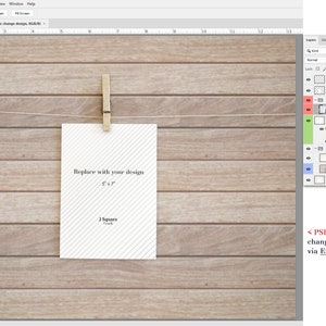 May include: A digital mockup template in PSD format featuring a vertical 5x7 inch white card with diagonal gray stripes, held by a wooden clothespin on a string against a light brown horizontal wood plank background, with a layer panel visible.