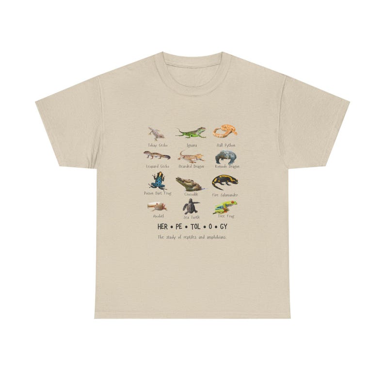 May include: Beige t-shirt featuring a collection of reptile and amphibian illustrations. The shirt includes the text "HER.PE.TOL.O.GY" and the phrase "The study of reptiles and amphibians."