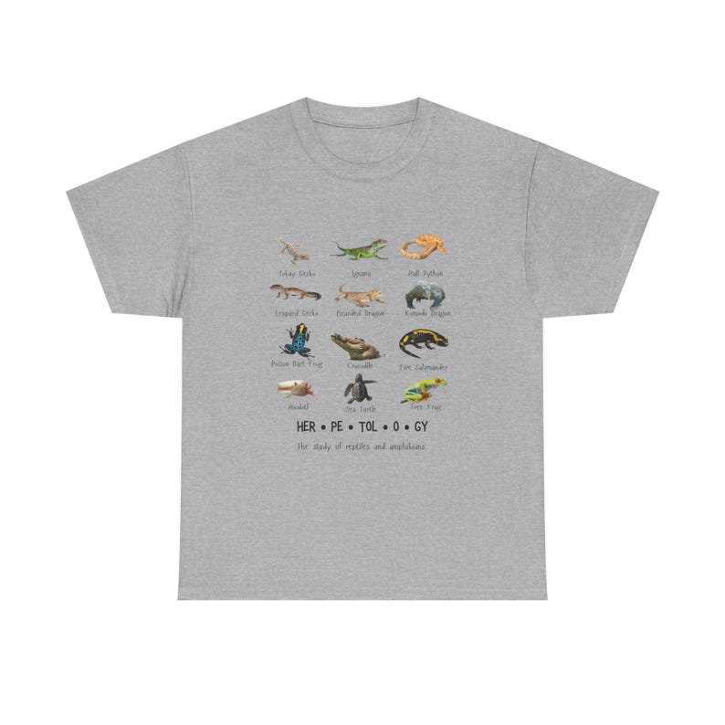 May include: A heather gray t-shirt featuring a colorful illustration of various reptiles and amphibians. The design includes images of lizards, frogs, and snakes, with the word "HERPETOLOGY" and the phrase "The study of reptiles and amphibians" printed below.
