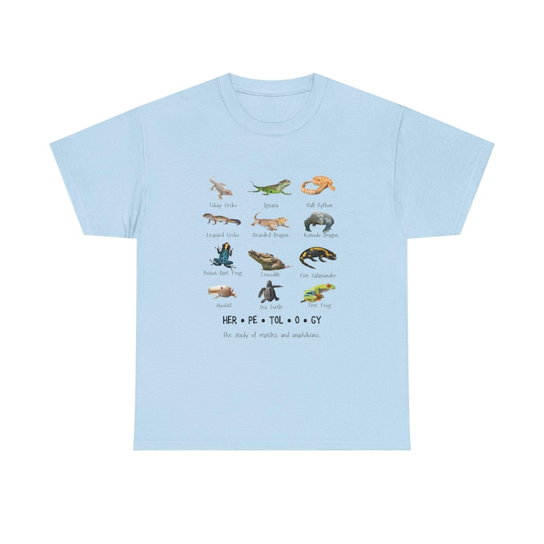 May include: Light blue t-shirt featuring a collection of reptile and amphibian illustrations. The shirt includes the word "HERPETOLOGY" and the phrase "The study of reptiles and amphibians."