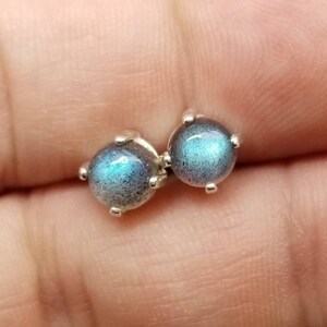 May include: A pair of silver stud earrings with iridescent blue labradorite gemstones.