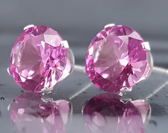 May include: A pair of silver stud earrings with pink round gemstones.