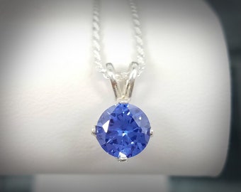May include: A silver chain necklace with a round blue gemstone pendant.