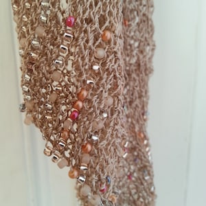 May include: A beige crocheted scarf with a fringe edge and colorful beads woven throughout.