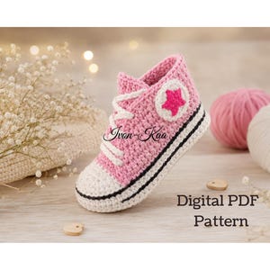Peut inclure: Une basket montante crochetée rose et blanche avec des lacets blancs, un bout blanc et un écusson circulaire avec une étoile rose sur le côté. Le texte "Ivon-Kaa" et "Digital PDF Pattern" est visible sur l'image.