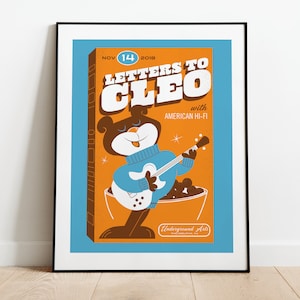 May include: A poster advertising a concert featuring Letters to Cleo with American Hi-Fi. The poster features a cartoon bear playing a guitar in a blue sweater. The poster is set against a blue and orange background. The text on the poster reads "Nov 14 2018 Letters to Cleo with American Hi-Fi Underground Arts".
