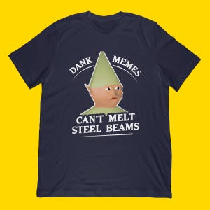 May include: Navy blue t-shirt featuring a meme graphic. The graphic includes a pixelated gnome with the text "DANK MEMES" above and "CAN'T MELT STEEL BEAMS" below. The shirt is made of a soft material.
