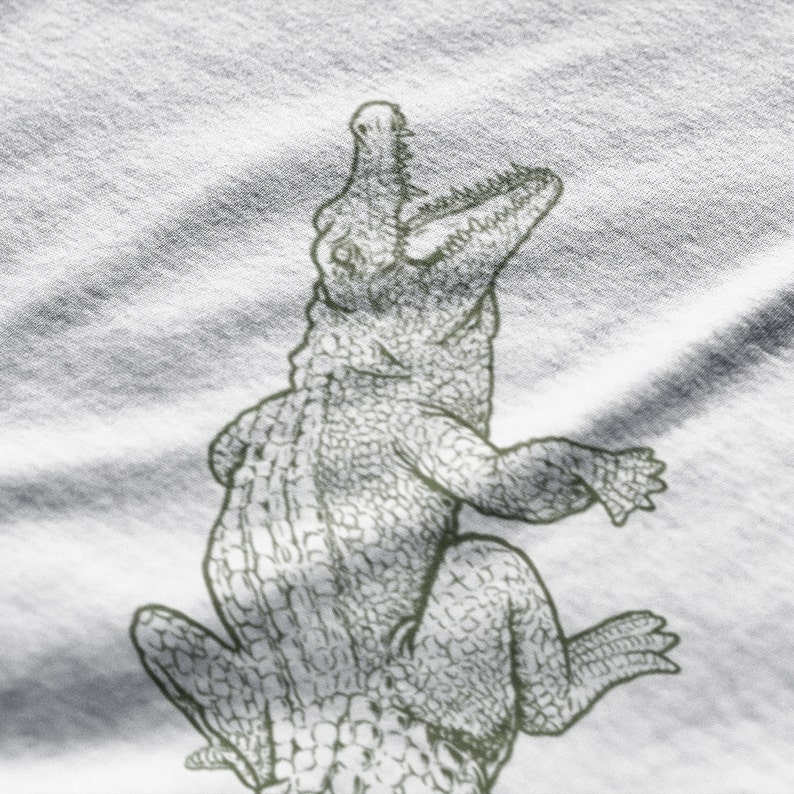 May include: A detailed illustration of an alligator in a sketch style. The alligator is depicted with its mouth open, revealing teeth, and its body is textured with scales. The image is in shades of gray and white.