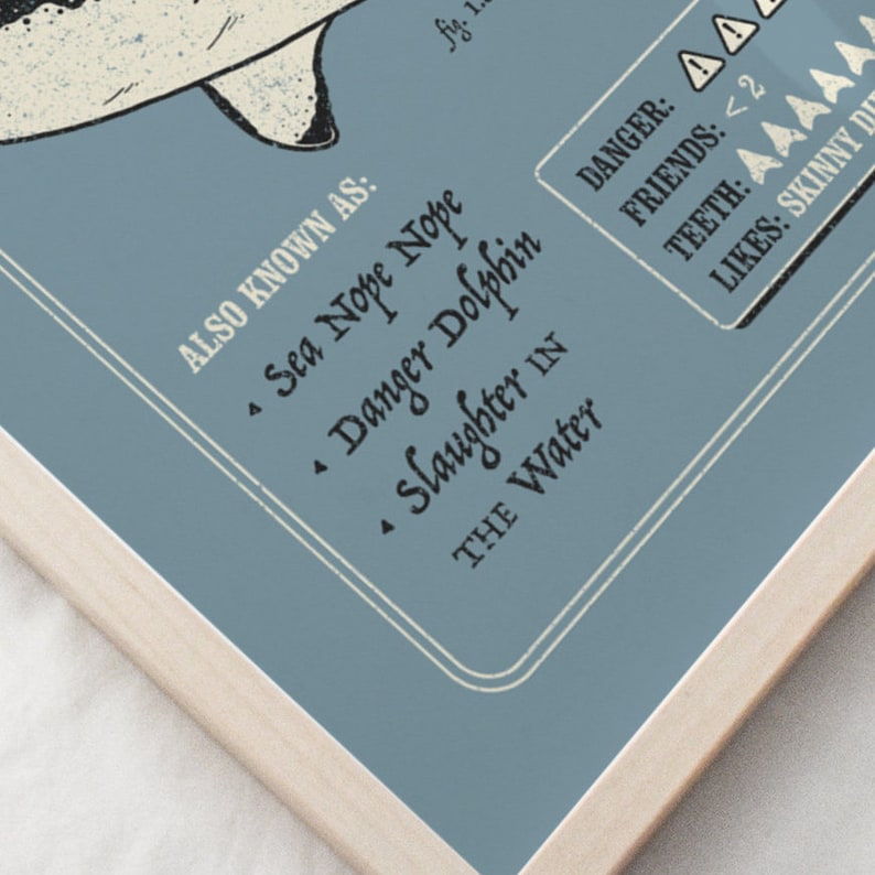 May include: A blue and white illustration of a shark with the text "ALSO KNOWN AS: &bull; Sea Nope Nope &bull; Danger Dolphin &bull; Slaughter IN THE Water" and a danger rating of 2.