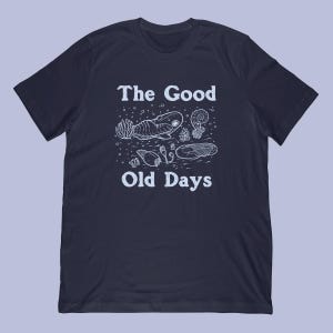 May include: Dark blue t-shirt with a white illustration of ancient marine life and the words "The Good Old Days". The design includes a trilobite, ammonite, and other fossilized creatures.
