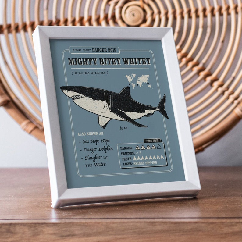 May include: A blue and white illustrated poster with the text "Know Your DANGER BOIS MIGHTY BITEY WHITEY (KILLIUS GILLIUS)". The poster features a cartoon illustration of a great white shark with the text "ALSO KNOWN AS: Sea Nope Nope Danger Dolphin Slaughter in the Water" and "FACT FILE Danger: AAAAA Friends: <2 Teeth: AAAAAAAA Likes: SKINNY DIPPING".
