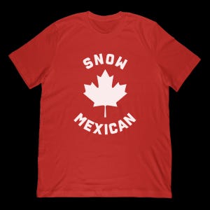 May include: Red t-shirt with a white maple leaf graphic. The text "SNOW" is above the leaf, and "MEXICAN" is below it, in a curved font. The shirt is made of a soft material.