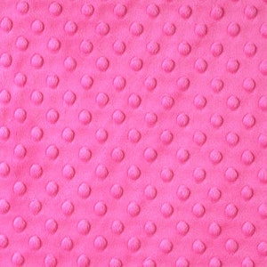 May include: A close-up of a pink fabric with a textured, raised dot pattern.