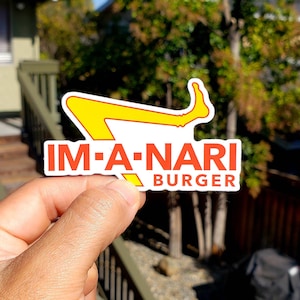 May include: A white sticker with a yellow and red logo that says "IM-A-NARI BURGER". The logo is a stylized image of a person's legs with one leg bent at the knee.