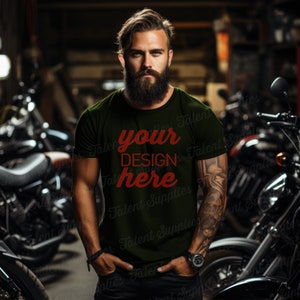 Op de afbeelding: Een man draagt een donkergroen T-shirt met de tekst "your design here" in rood. Hij staat voor een rij motorfietsen.