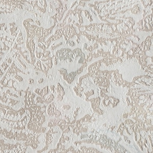 May include: A close-up of a textured white surface with a pattern of raised lines and swirls. The surface has a subtle beige hue and a rough, uneven texture.