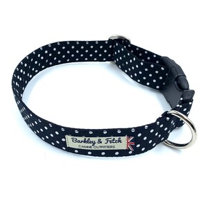 May include: Black and white polka dot dog collar with a silver buckle and a silver D-ring. The collar has a label that reads "Barkley & Fetch Canine Outfitters".