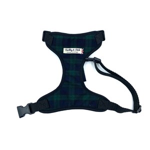 May include: Black and green tartan dog harness with a black adjustable strap and a black buckle. The harness has a label that says "Barkley & Fitch Canine Outfitters".