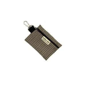 May include: A small, rectangular pouch with a brown and black houndstooth pattern. It has a black zip, a silver-coloured clip, and a label that reads "Barkly & Fitch CANINE OUTFITTERS".