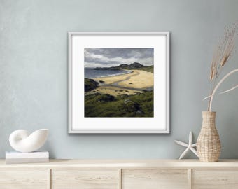 May include: A framed painting of a beach scene with a curved shoreline, green hills, and a cloudy sky.