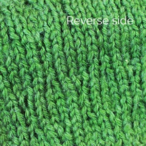 K&ouml;nnte beinhalten: Nahaufnahme eines gr&uuml;nen Strickstoffes. Der Stoff hat eine strukturierte, gerippte Struktur. Der Text "Reverse side" ist in der oberen rechten Ecke des Bildes sichtbar.