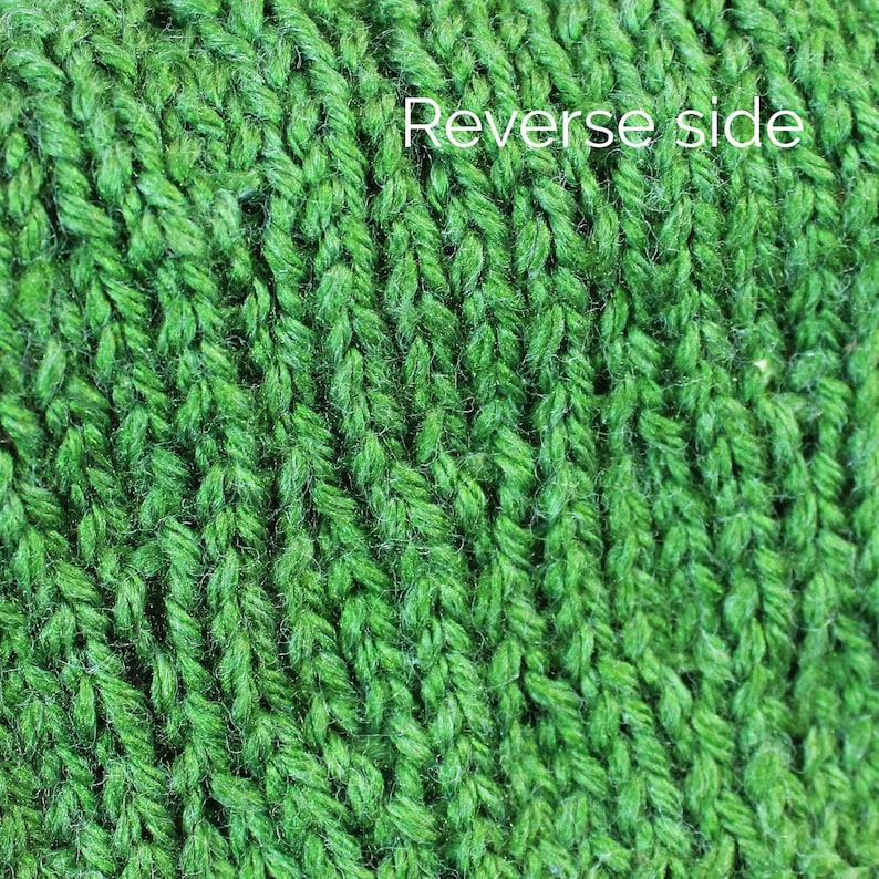 K&ouml;nnte beinhalten: Nahaufnahme eines gr&uuml;nen Strickstoffes. Der Stoff hat eine strukturierte, gerippte Struktur. Der Text "Reverse side" ist in der oberen rechten Ecke des Bildes sichtbar.