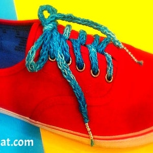 May include: Red canvas sneakers with blue laces. The laces are tied in a criss-cross pattern and the shoes are on a yellow and blue background.
