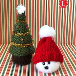 Puede incluir: Un &aacute;rbol de Navidad de punto verde con una estrella brillante en la parte superior y un mu&ntilde;eco de nieve de punto blanco que lleva un gorro rojo de punto con un pomp&oacute;n blanco.