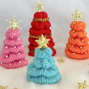 May include: Four crocheted Christmas trees in pink, red, orange, and blue. Each tree is decorated with gold stars and beads.