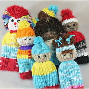 May include: A group of seven knitted dolls with different colored yarn and facial features. The dolls are wearing various hats and clothing, including a red and white striped hat, a blue and yellow hat, and a red and white striped dress.
